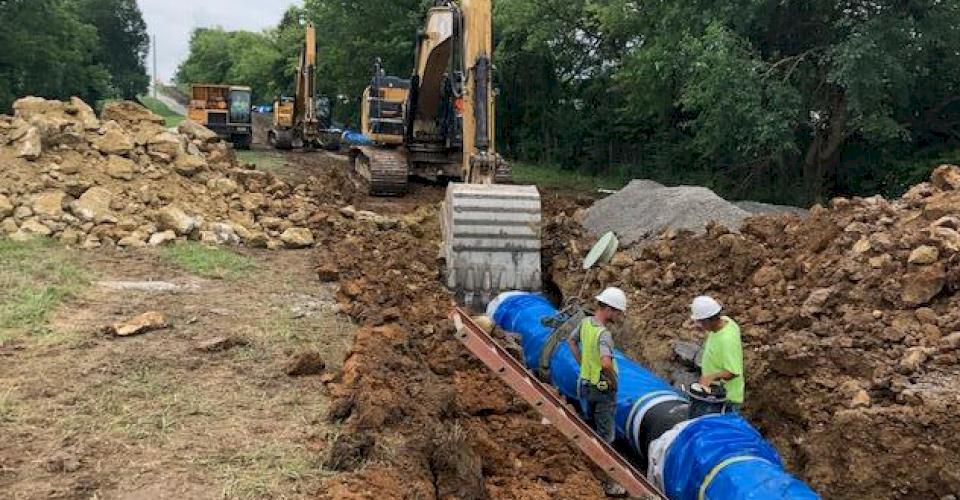 Crews install ductile iron pipe with polyethylene encsement.