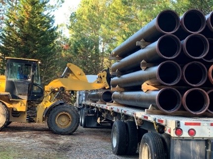 Ductile iron pipe is off-loaded from a truck.