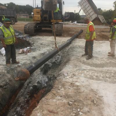 Placing the first section of DI pipe with puller head into the ditch during an HDD install.